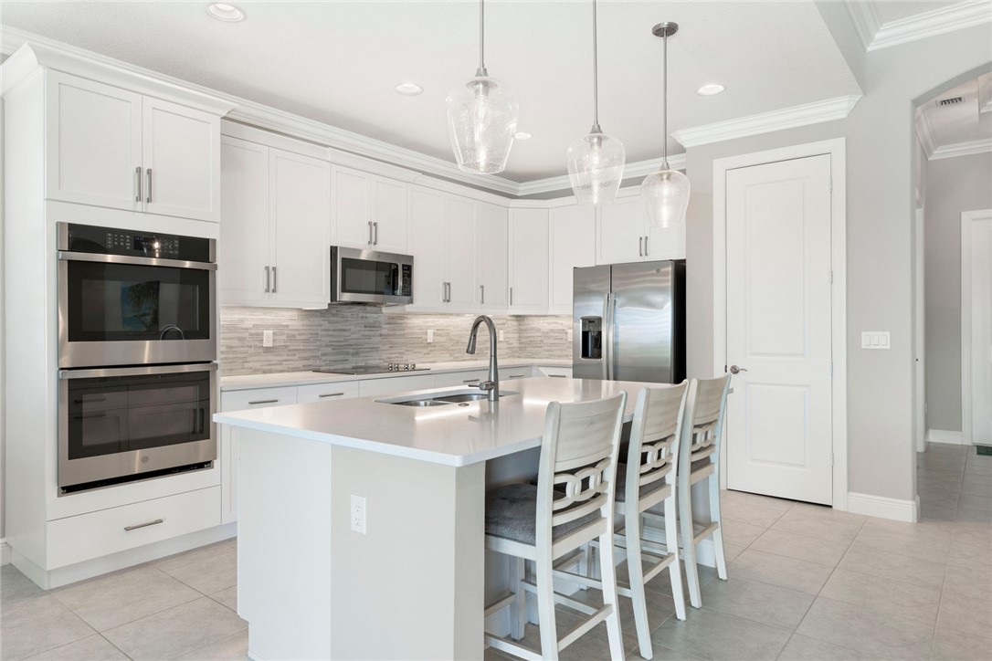 7203 33rd Square Vero Beach, FL 32967 - Photo 5 of 28 a kitchen with stainless steel appliances granite countertop a stove a sink and a refrigerator with white cabinets