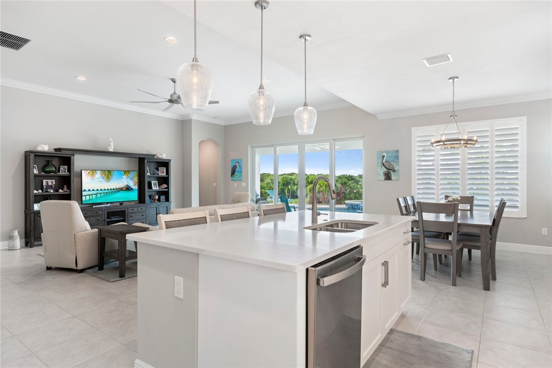 7203 33rd Square Vero Beach, FL 32967 - Photo 6 of 28 a kitchen with stainless steel appliances granite countertop a stove a sink a kitchen island a table and chairs