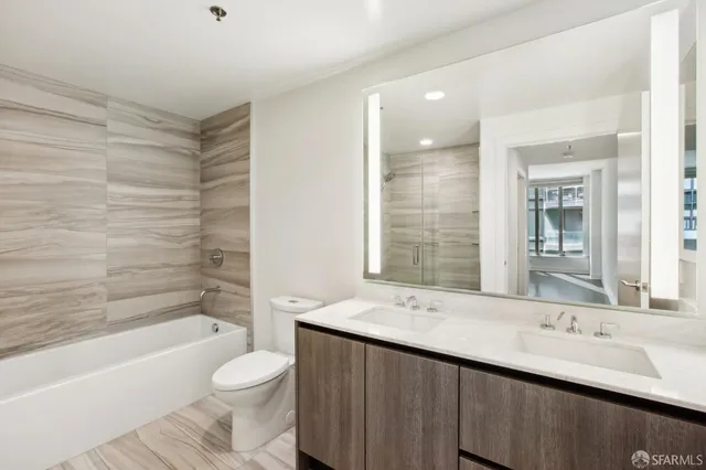 a bathroom with a double vanity sink toilet mirror and bathtub