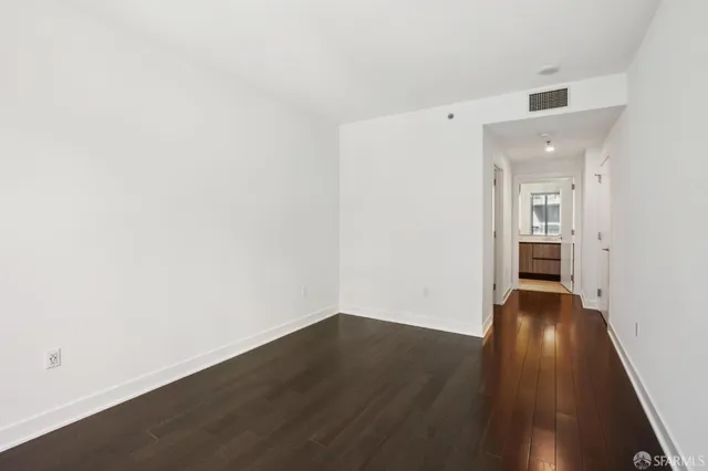 a view of a hallway with wooden floor and a bathroom