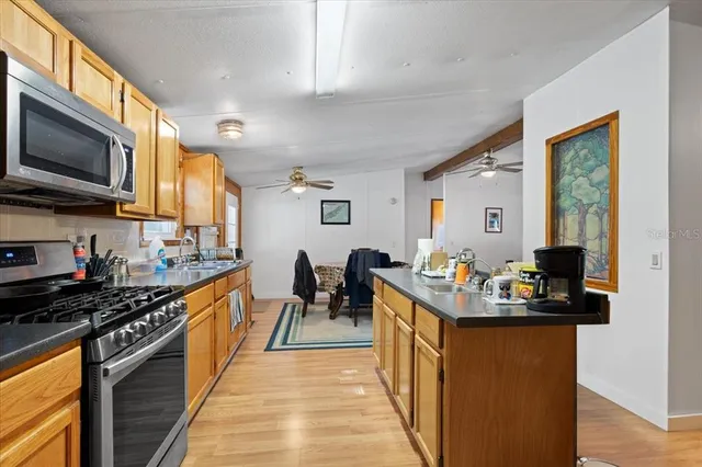 a kitchen with stainless steel appliances kitchen island granite countertop a stove top oven a sink dishwasher a dining table and chairs with wooden floor