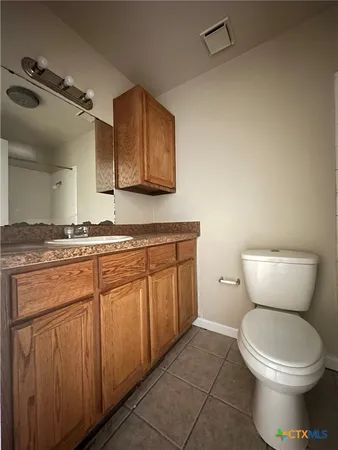 a bathroom with a granite countertop toilet sink and mirror