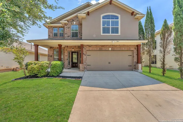 a view of a house with a yard plants and large tree