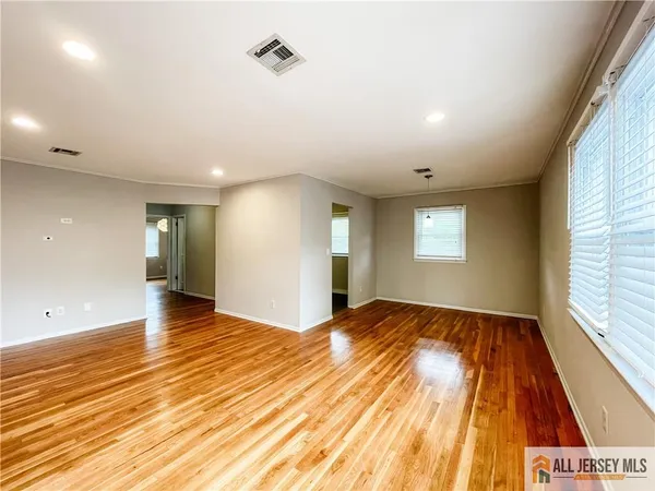 a view of an empty room and window and wooden floor