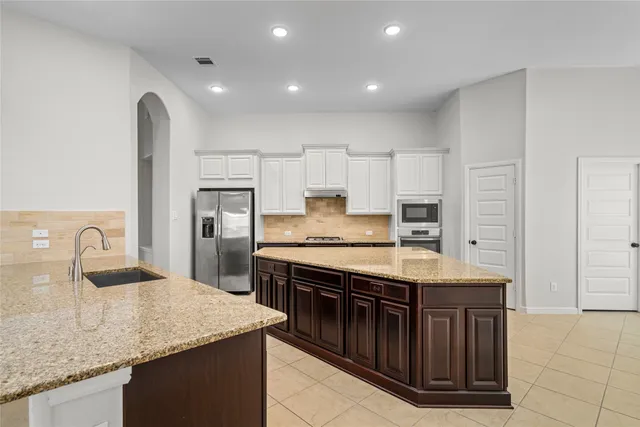 a kitchen with stainless steel appliances granite countertop a stove a sink and a refrigerator