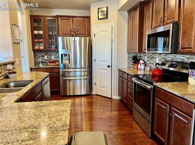 a kitchen with stainless steel appliances granite countertop a refrigerator and a stove top oven