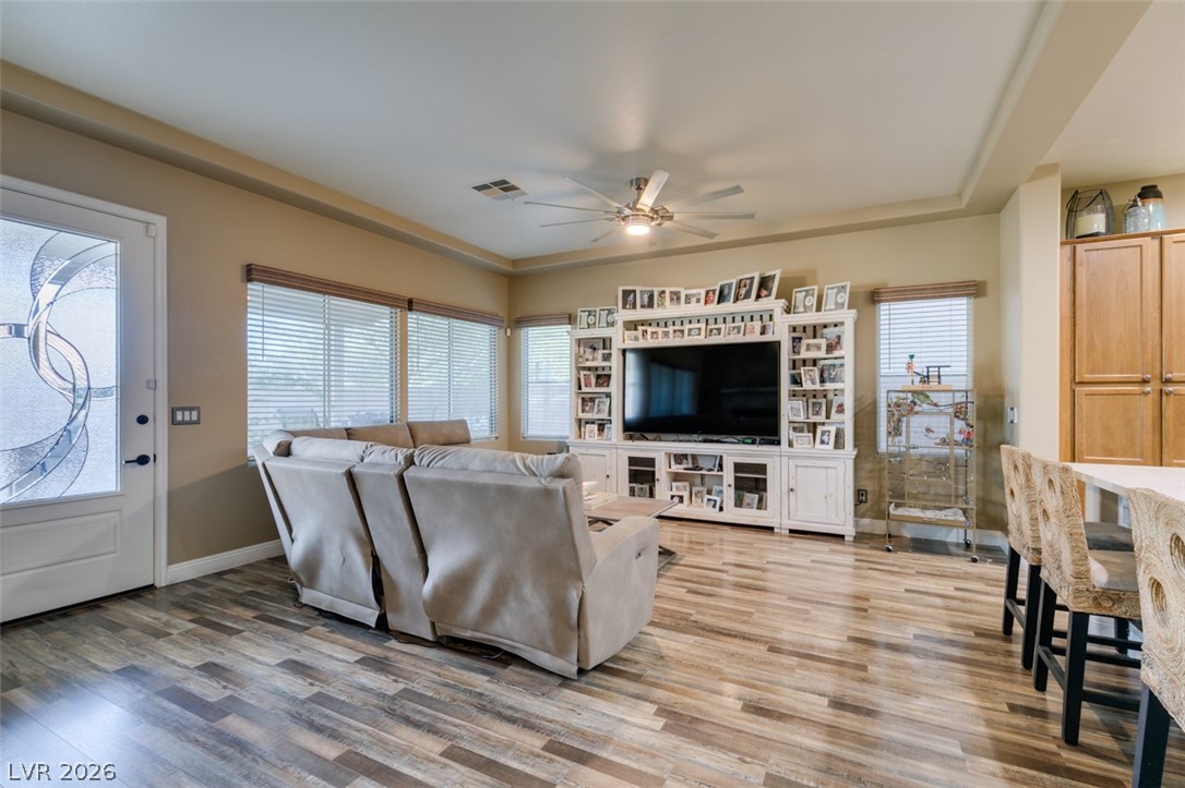 7524 Midnight Rambler Street Las Vegas, NV 89149 - Photo 14 of 51 Natural light illuminates the open-concept living space, featuring wide plank flooring and a stylish ceiling fan.