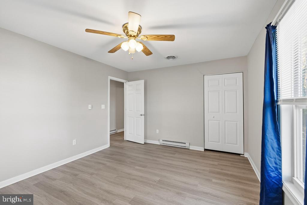 1326 Perrys Corner Road Grasonville, MD 21638 - Photo 29 of 35 an empty room with wooden floor fan and windows