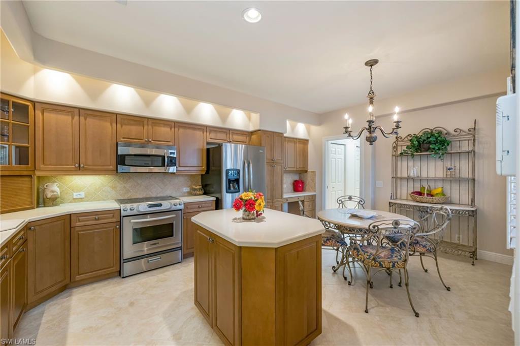 6012 Fairway Court Naples, FL 34110 - Photo 8 of 38 a kitchen with kitchen island a sink stove and chairs with wooden floor