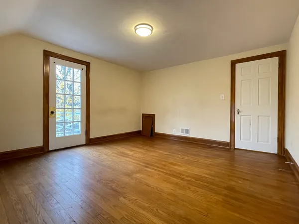a view of an empty room with wooden floor and a window