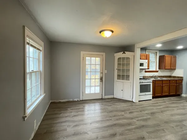 a view of an empty room with a window and kitchen view