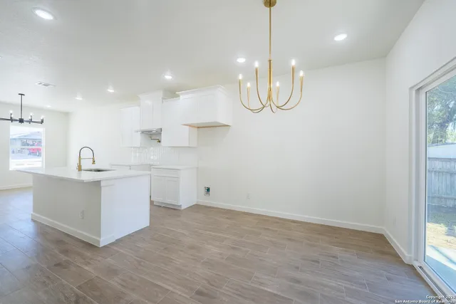 a kitchen with white cabinets and wooden floor