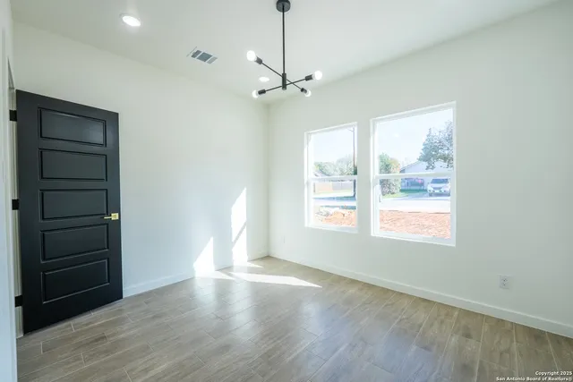 a view of an empty room with a window and wooden floor