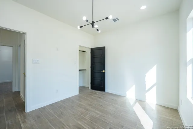 a view of empty room with wooden floor and fan