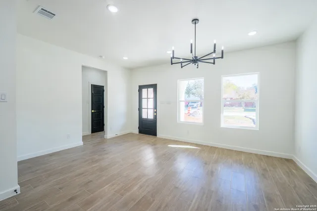 an empty room with wooden floor ceiling fan and windows