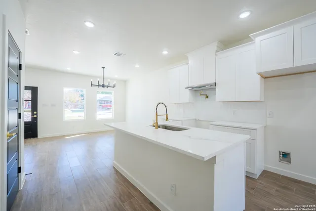a kitchen with a sink a refrigerator and white cabinets