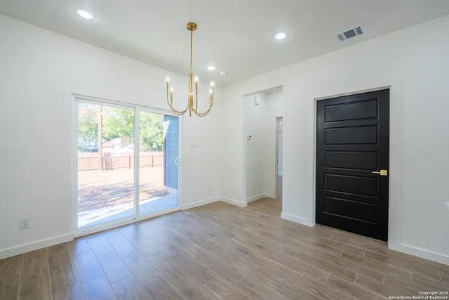 an empty room with wooden floor cabinet and windows