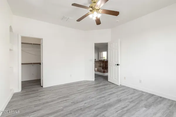 an empty room with wooden floor closet and ceiling fan