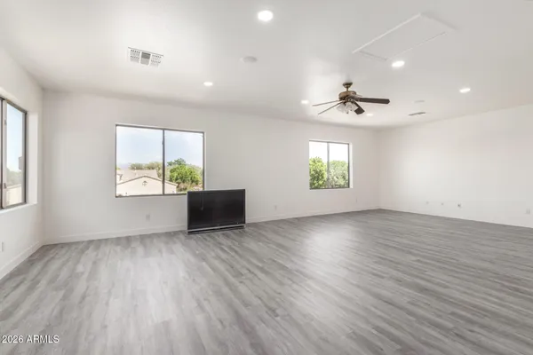 an empty room with windows and ceiling fan