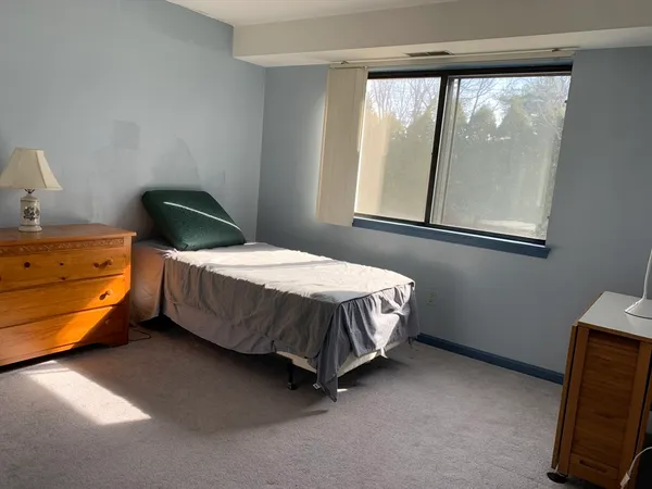 a bedroom with a bed chair and mirror