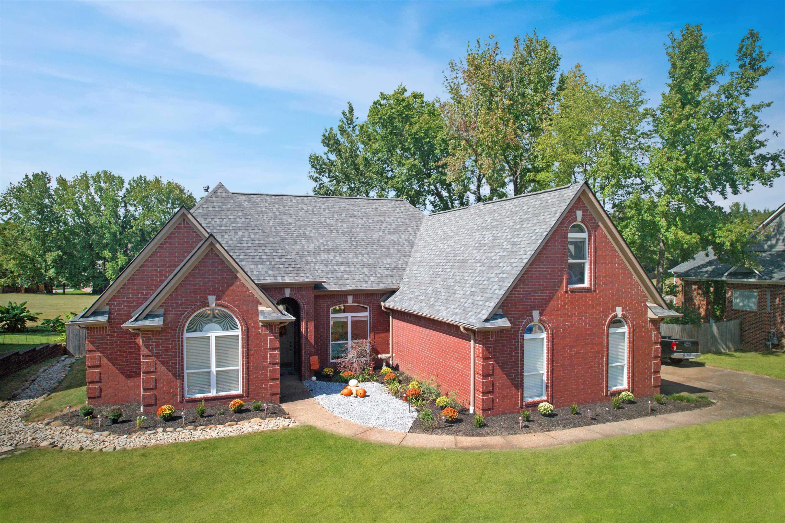 View of front of house featuring brick siding, a front yard, and a shingled roof