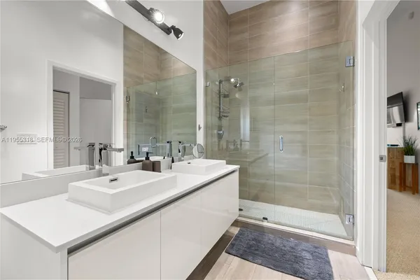 a view of a hallway with wooden floor and a bathroom