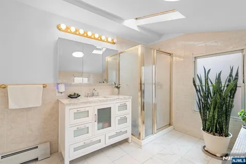 a bathroom with a double vanity sink a potted plant and a glass door shower