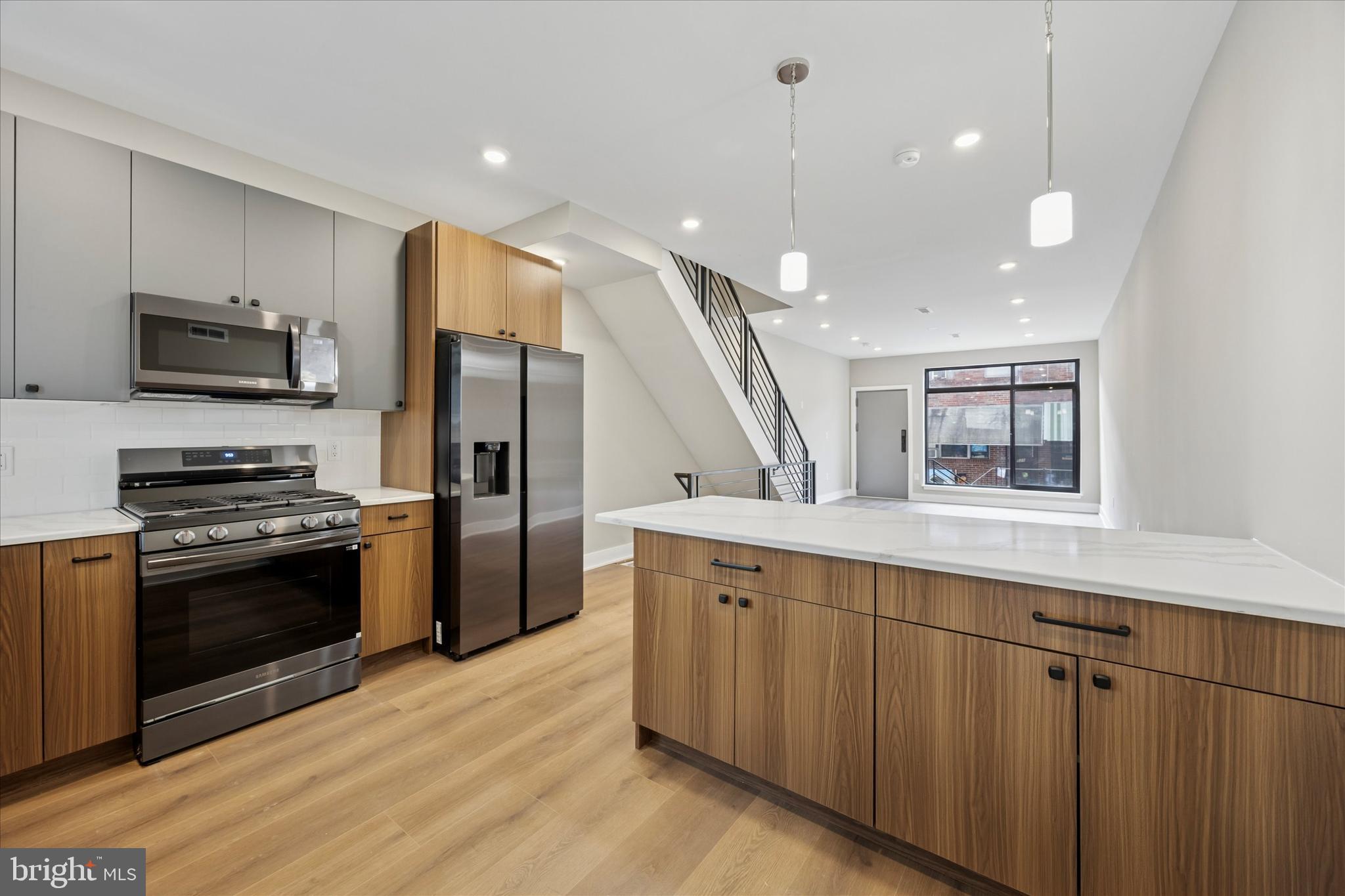 523 Gerritt Street Philadelphia, PA 19147 - Photo 10 of 35 a large kitchen with stainless steel appliances kitchen island granite countertop a refrigerator a stove a microwave and a view of living room