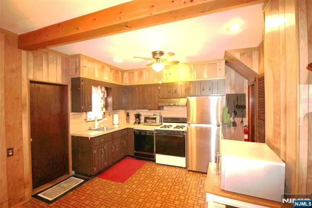 a kitchen with stainless steel appliances a stove a refrigerator and a fireplace
