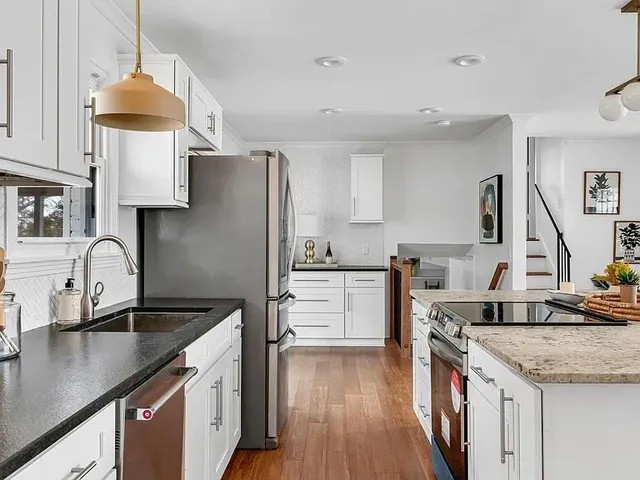 a kitchen with a sink dishwasher a stove top oven a refrigerator a sink and dishwasher with wooden floor