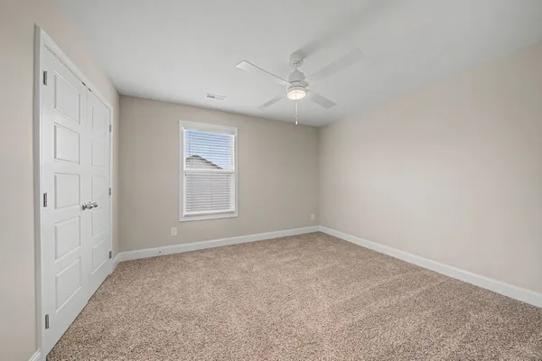 an empty room with a ceiling fan and a window