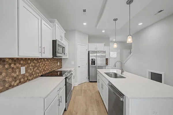 a kitchen that has a sink a microwave oven a stove and white cabinets