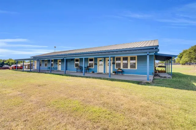 a view of swimming pool with lawn chairs and large trees