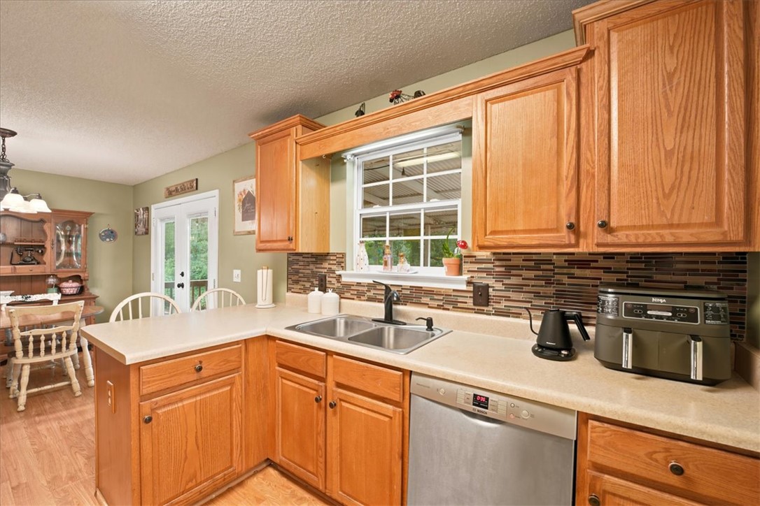 520 Sharon Lane Seneca, SC 29678 - Photo 15 of 48 A well-lit kitchen with natural wood cabinetry and a functional double sink, perfect for daily routines.