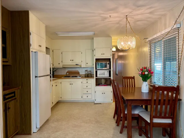 a kitchen with granite countertop a refrigerator a stove a dining table and chairs with wooden floor