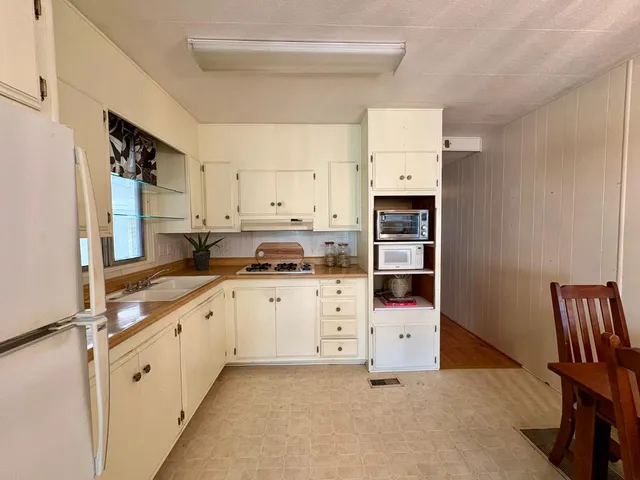 a kitchen with granite countertop a refrigerator and a stove top oven