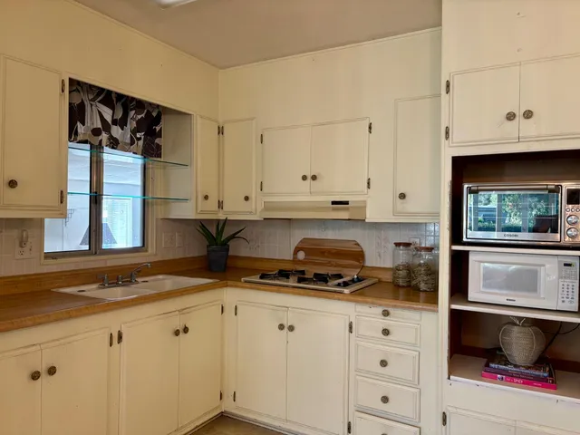 a kitchen with granite countertop white cabinets and a stove a sink with dishwasher