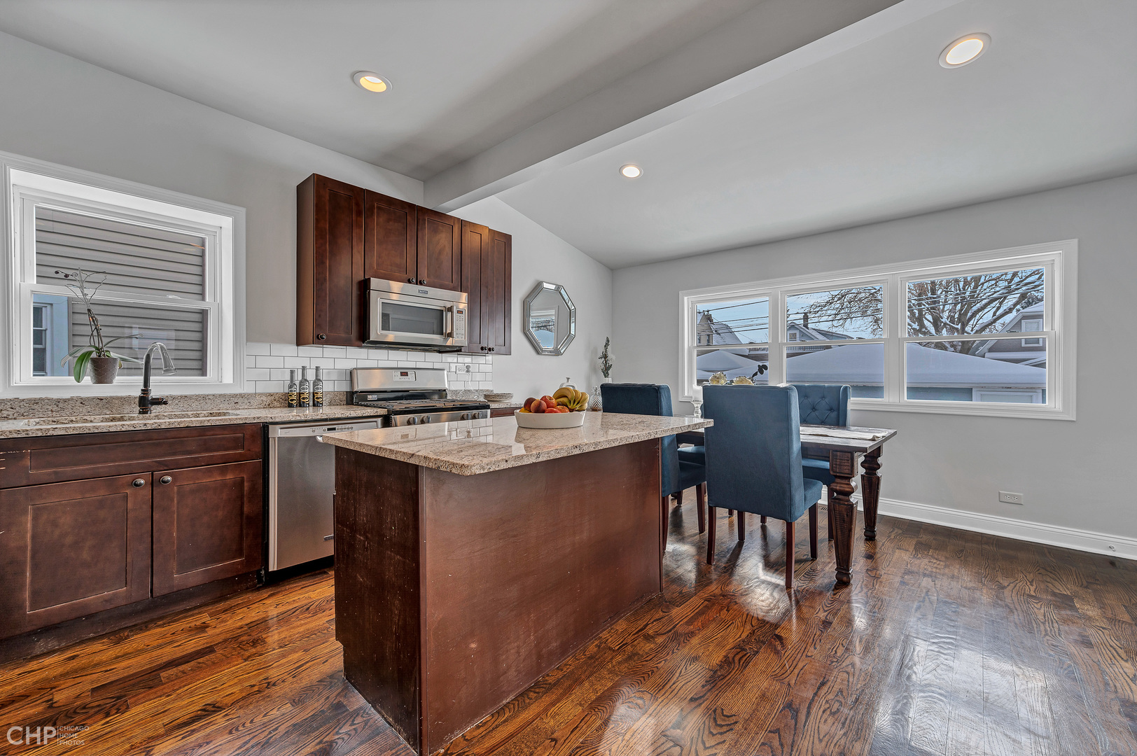 4841 West Berenice Avenue Chicago, IL 60641 - Photo 7 of 34 a kitchen with stainless steel appliances granite countertop a stove top oven a sink dishwasher a dining table and chairs with wooden floor