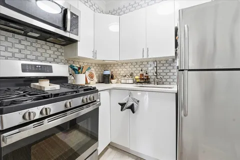 a kitchen with stainless steel appliances a refrigerator a stove and white cabinets