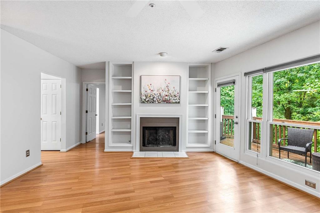 490 Sherman Way Decatur, GA 30033 - Photo 17 of 44 an empty room with wooden floor fireplace cabinet and windows