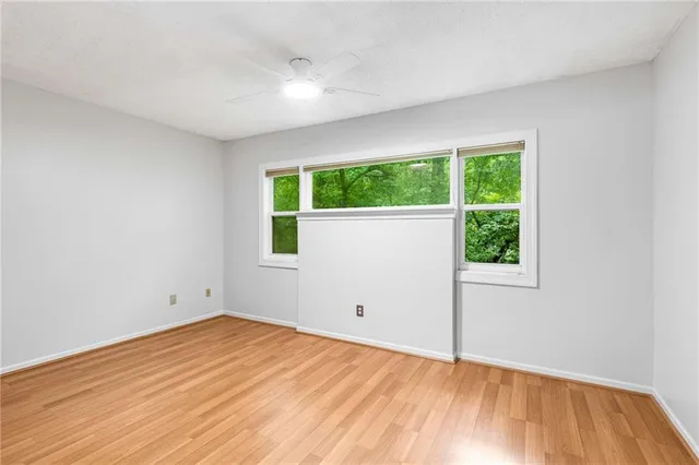 a view of empty room with wooden floor and fan