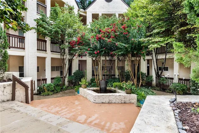 a view of a white house with a yard and table and chairs under an umbrella