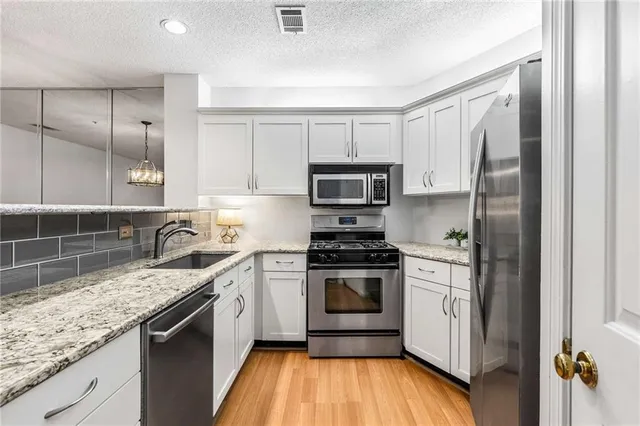 a kitchen with stainless steel appliances granite countertop a stove a sink and a refrigerator