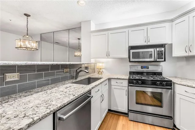 a kitchen with granite countertop a sink a stove and microwave