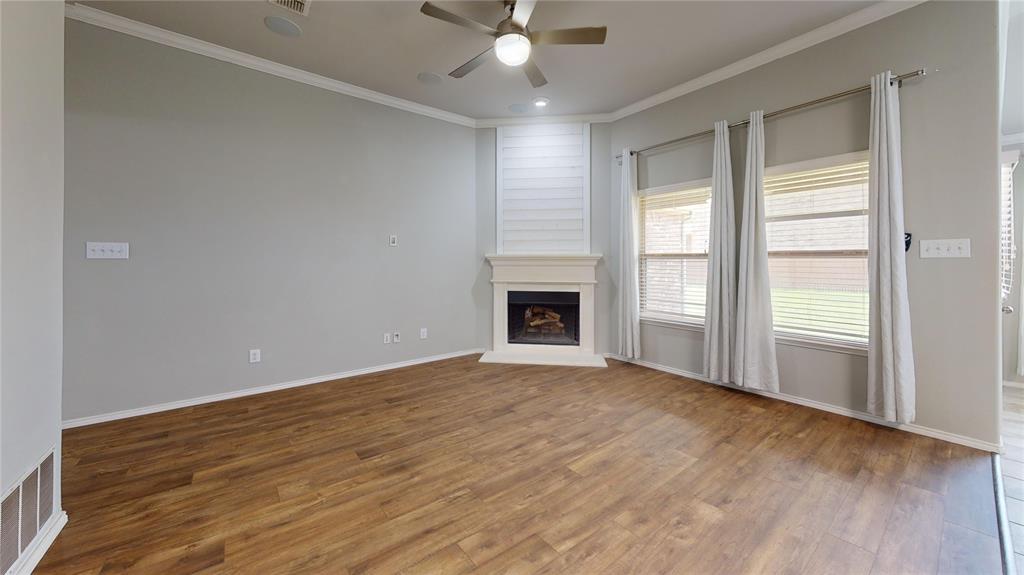 3101 Buckthorn Street Forney, TX 75126 - Photo 33 of 40 Living area featuring wood-finish flooring, a corner fireplace with a white mantel, ceiling fan, crown molding, and multiple windows with blinds