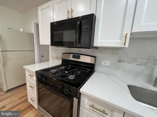 a kitchen with stainless steel appliances granite countertop white cabinets and a stove top oven