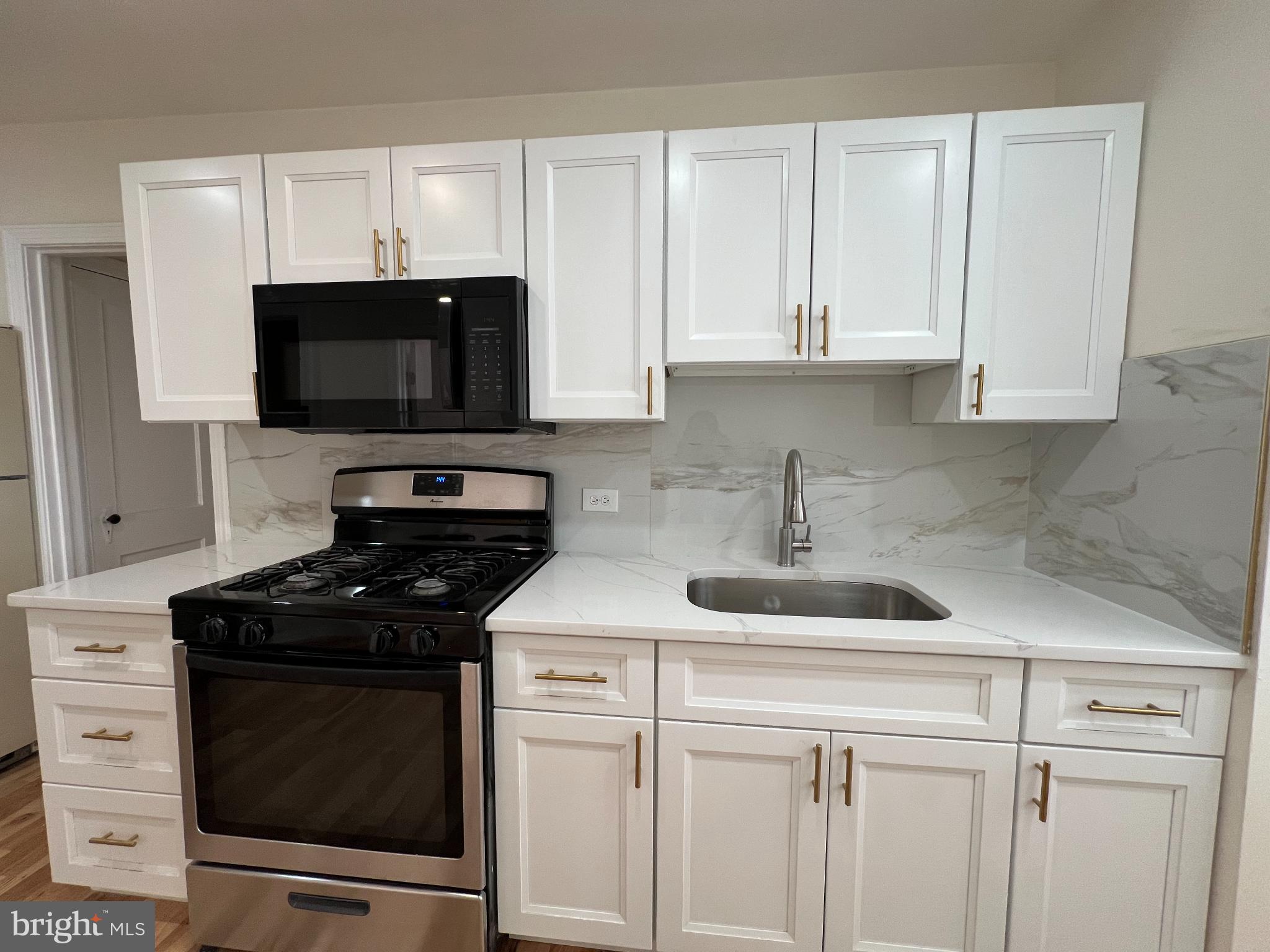 4345 Loring Street Philadelphia, PA 19136 - Photo 5 of 16 a kitchen with white cabinets and black appliances