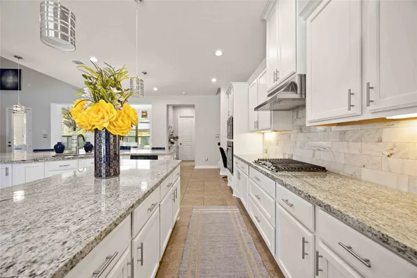 a kitchen with kitchen island granite countertop a sink a counter top space and cabinets