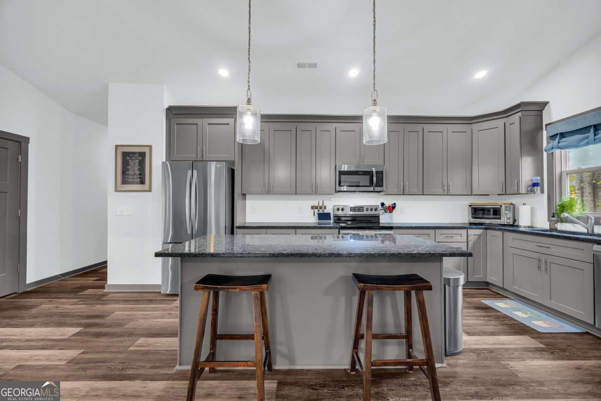 153 North Point Circle Hartwell, GA 30643 - Photo 18 of 60 a kitchen with stainless steel appliances granite countertop a kitchen island a stove a refrigerator and white cabinets with wooden floors