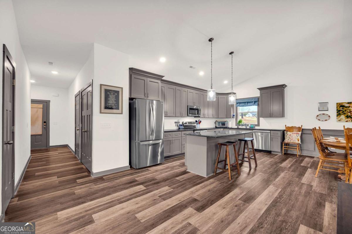 153 North Point Circle Hartwell, GA 30643 - Photo 27 of 60 a kitchen with stainless steel appliances kitchen island granite countertop a refrigerator oven a sink dishwasher and white cabinets with wooden floor